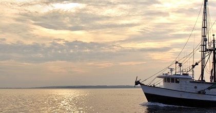 Fishing trawler on the water and dramatic clouds at sunrise